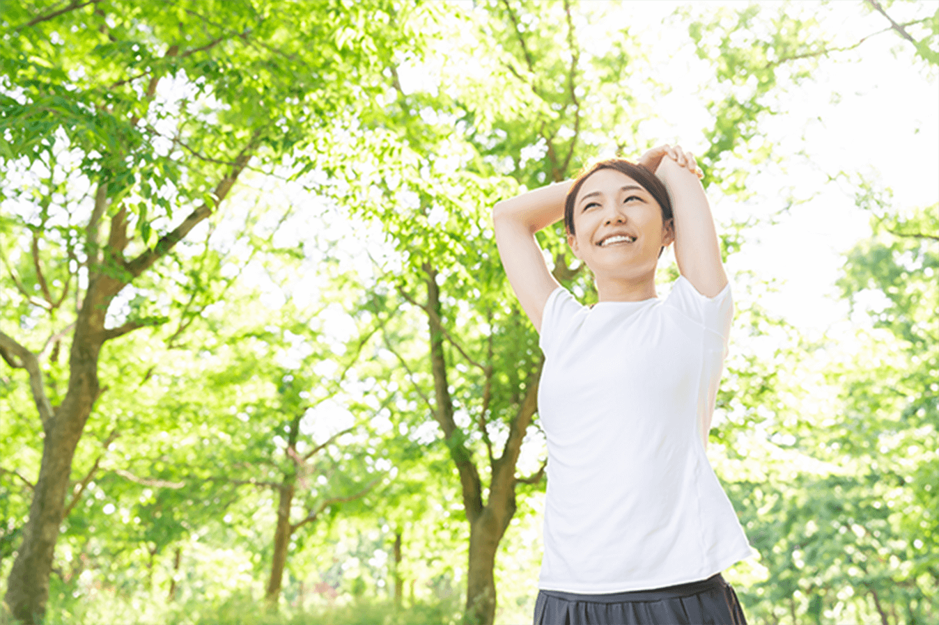 緑の中でストレッチをしている女性